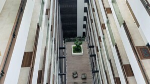 A modern building with a central atrium, multiple floors, and a fire extinguisher on the right.
