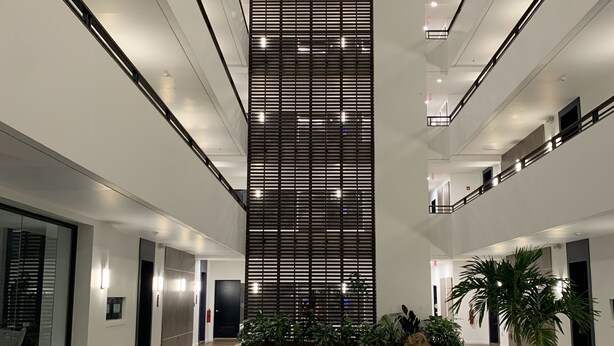A modern interior with a central atrium, wooden flooring, and a seating area with chairs and a table.