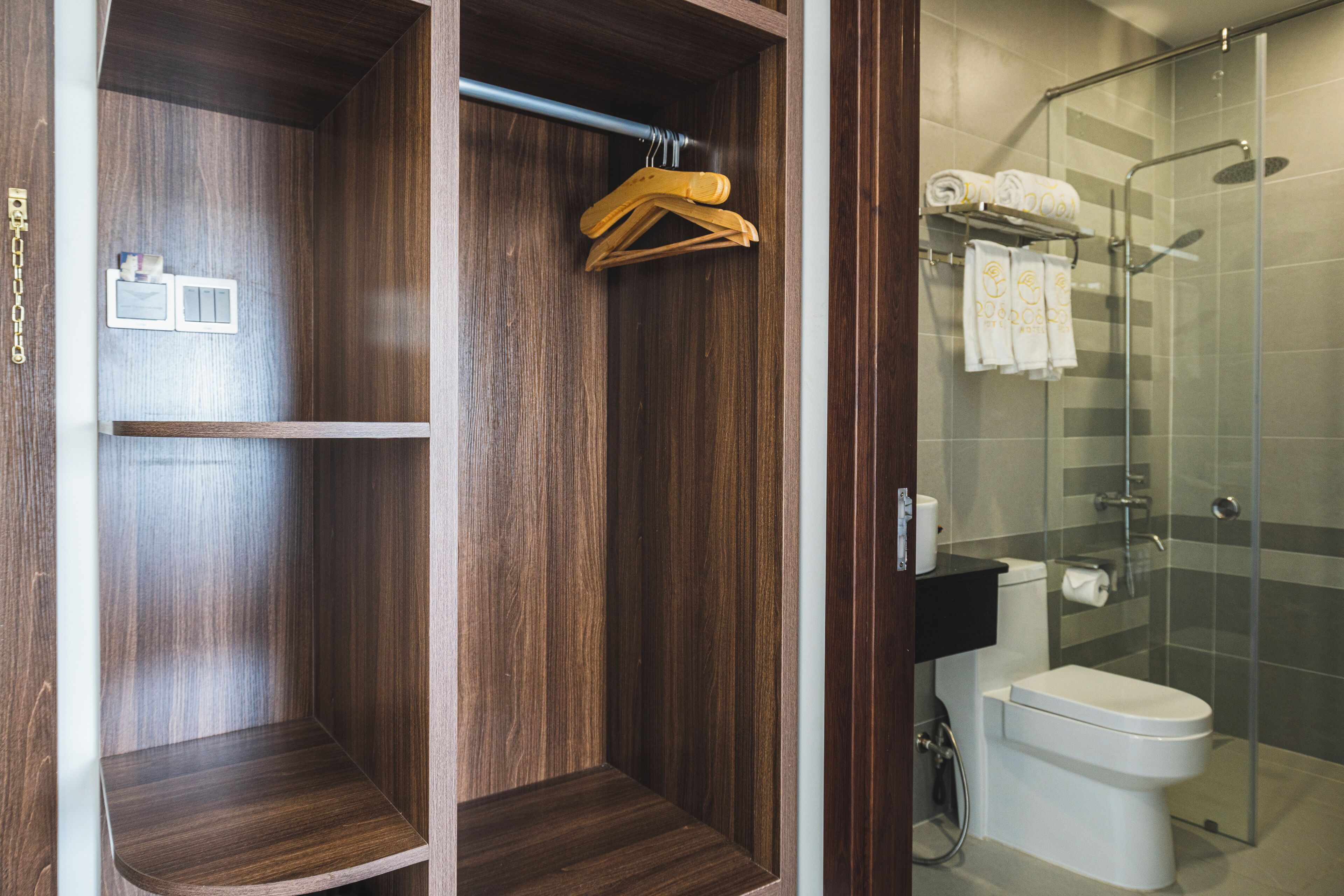 A bathroom with a glass shower enclosure, a toilet, and a wooden vanity with a towel rack.