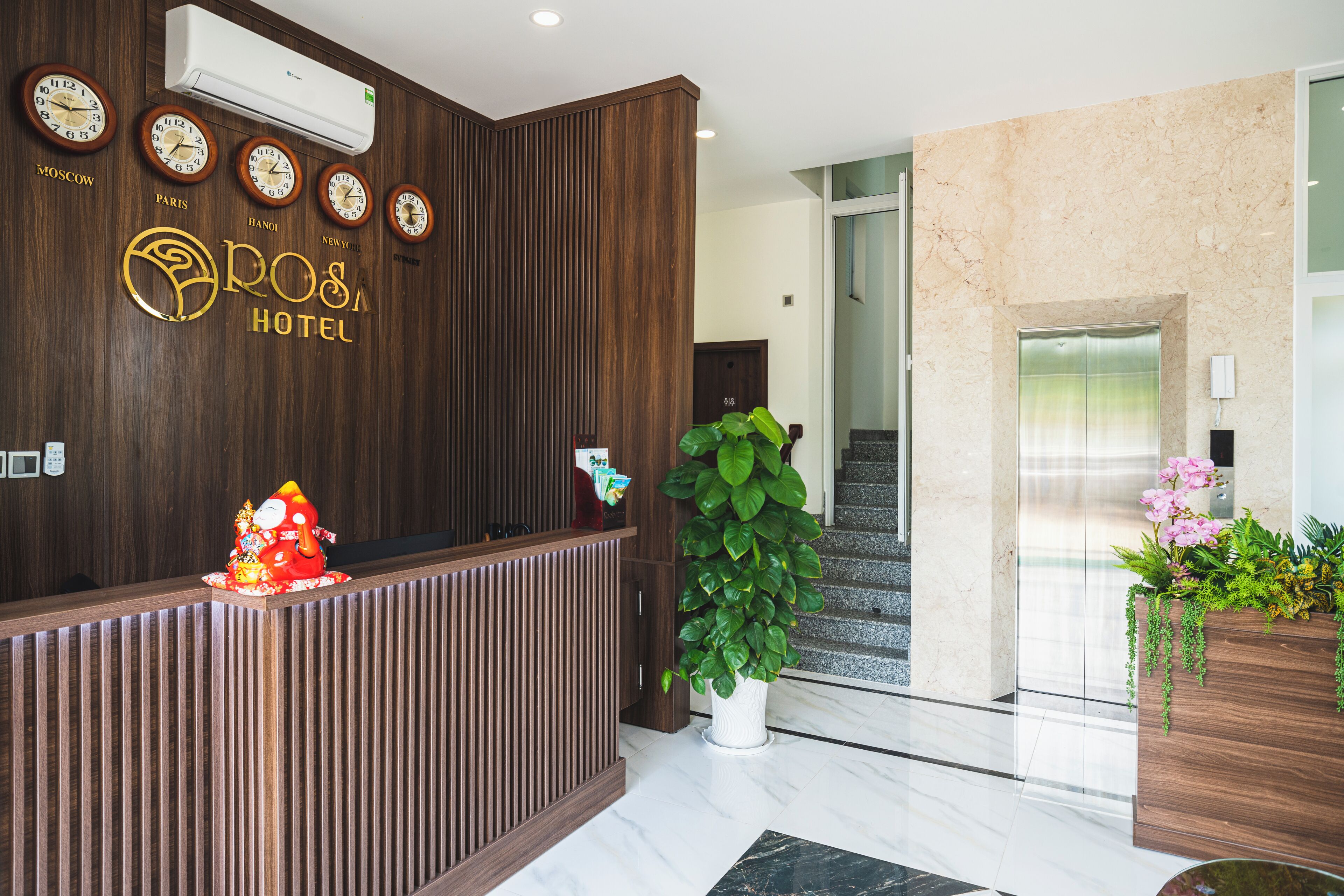 A reception area with a wooden reception desk, a wall clock, and a potted plant.