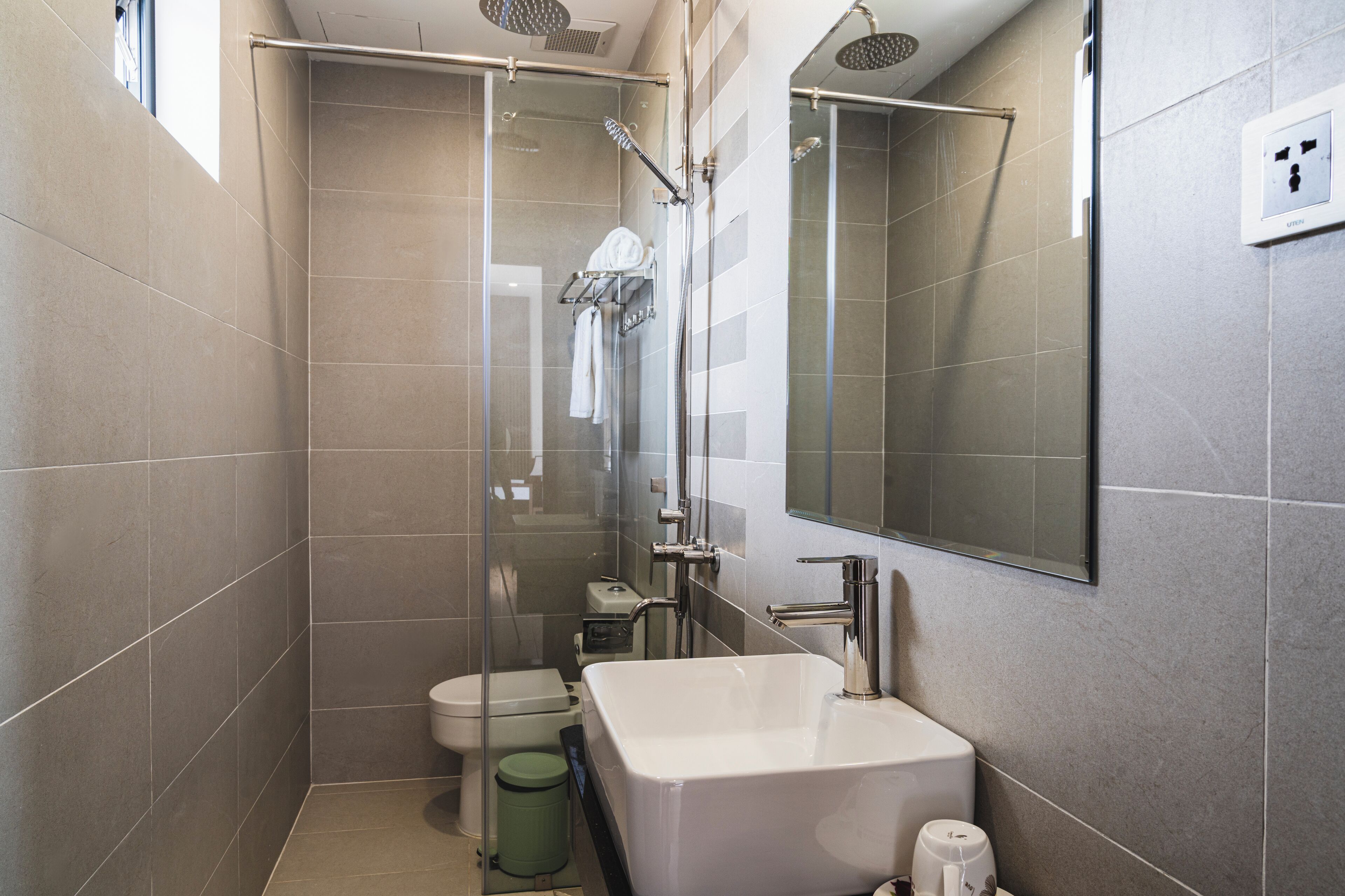 A modern bathroom with a glass-enclosed shower, a white sink, and a toilet.