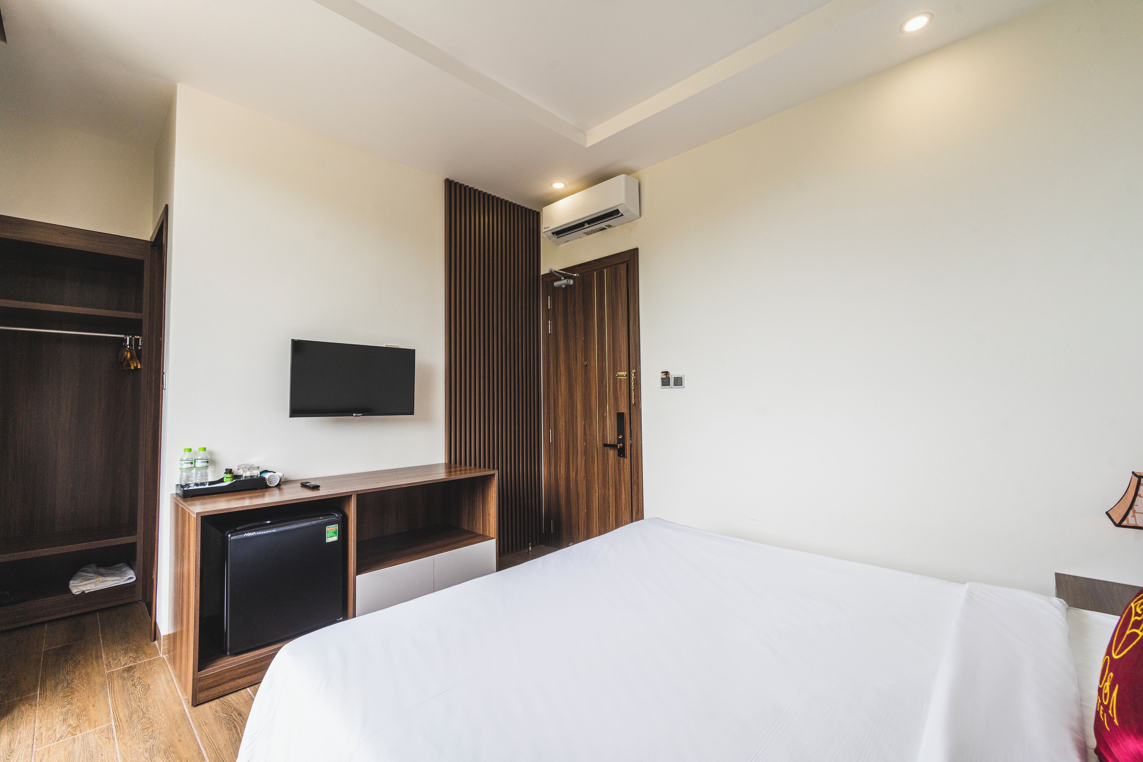 Habitación de hotel con una cama, un escritorio con ordenador, un televisor y un armario.