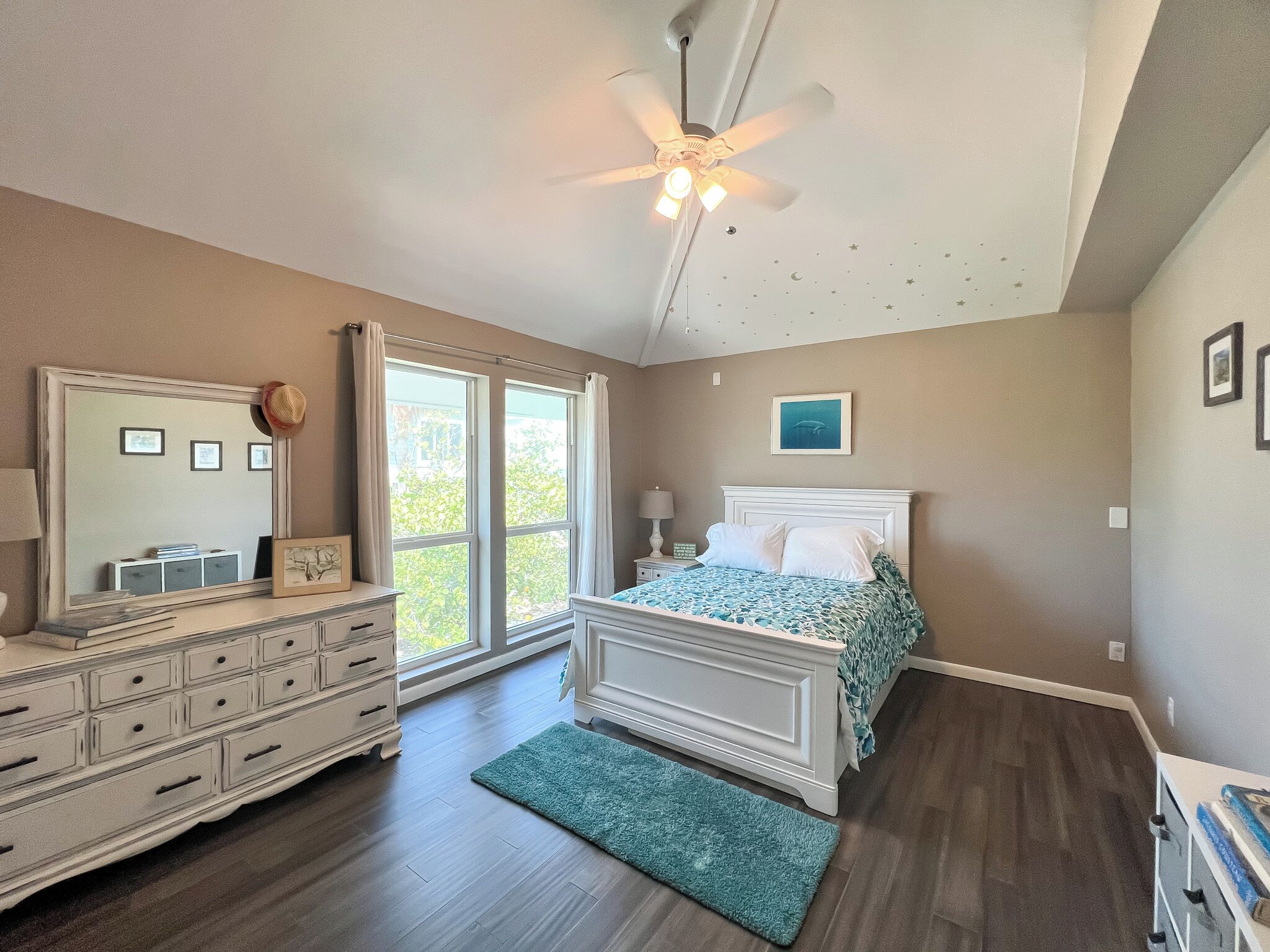 A bedroom with a bed, dresser, and a ceiling fan.
