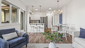 A modern kitchen with white cabinets, stainless steel appliances, and a dining area with white chairs. - Top Floor Mountain View with Pool & Hot tubs (Canmore)
