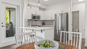 A modern kitchen with white cabinetry, stainless steel appliances, and pendant lighting. - Top Floor Mountain View with Pool & Hot tubs (Canmore)