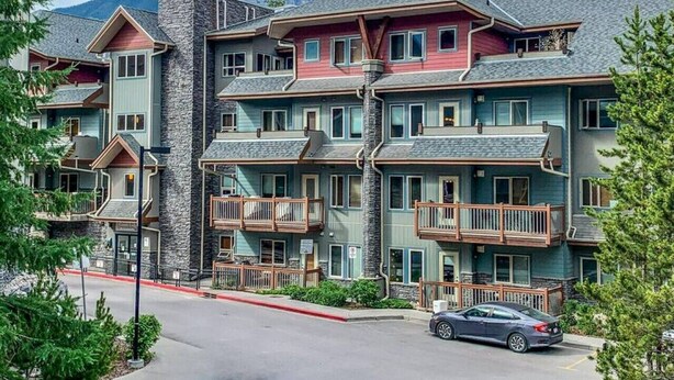 A multi-story hotel with balconies and a mountain backdrop. - Top Floor Mountain View with Pool & Hot tubs (Canmore)