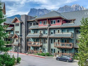 Een hotel met meerdere verdiepingen, balkons en een berg op de achtergrond.