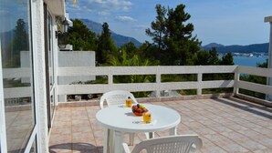 A balcony with a white railing, a round table with chairs, and a fruit bowl with drinks. - The only apartment in a detached house (Bar)