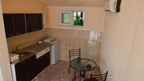A compact kitchen with dark cabinets, a small window, and a dining area with two chairs. - The only apartment in a detached house (Bar)