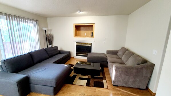 A living room with a sofa, a coffee table, and a fireplace. - Spacious & Conveniently Located 4/2.5 House (Tigard)
