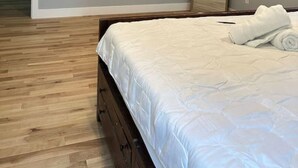 Un dormitorio con una cama, un televisor de pantalla plana, un espejo y suelo de madera.