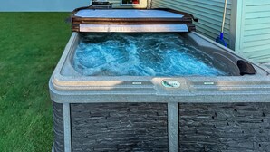 Un jacuzzi con revestimiento de piedra y tapa de madera.