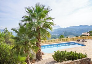 Ein Pool mit Blick auf eine Berglandschaft, umgeben von einem gelben Zaun und Palmen.