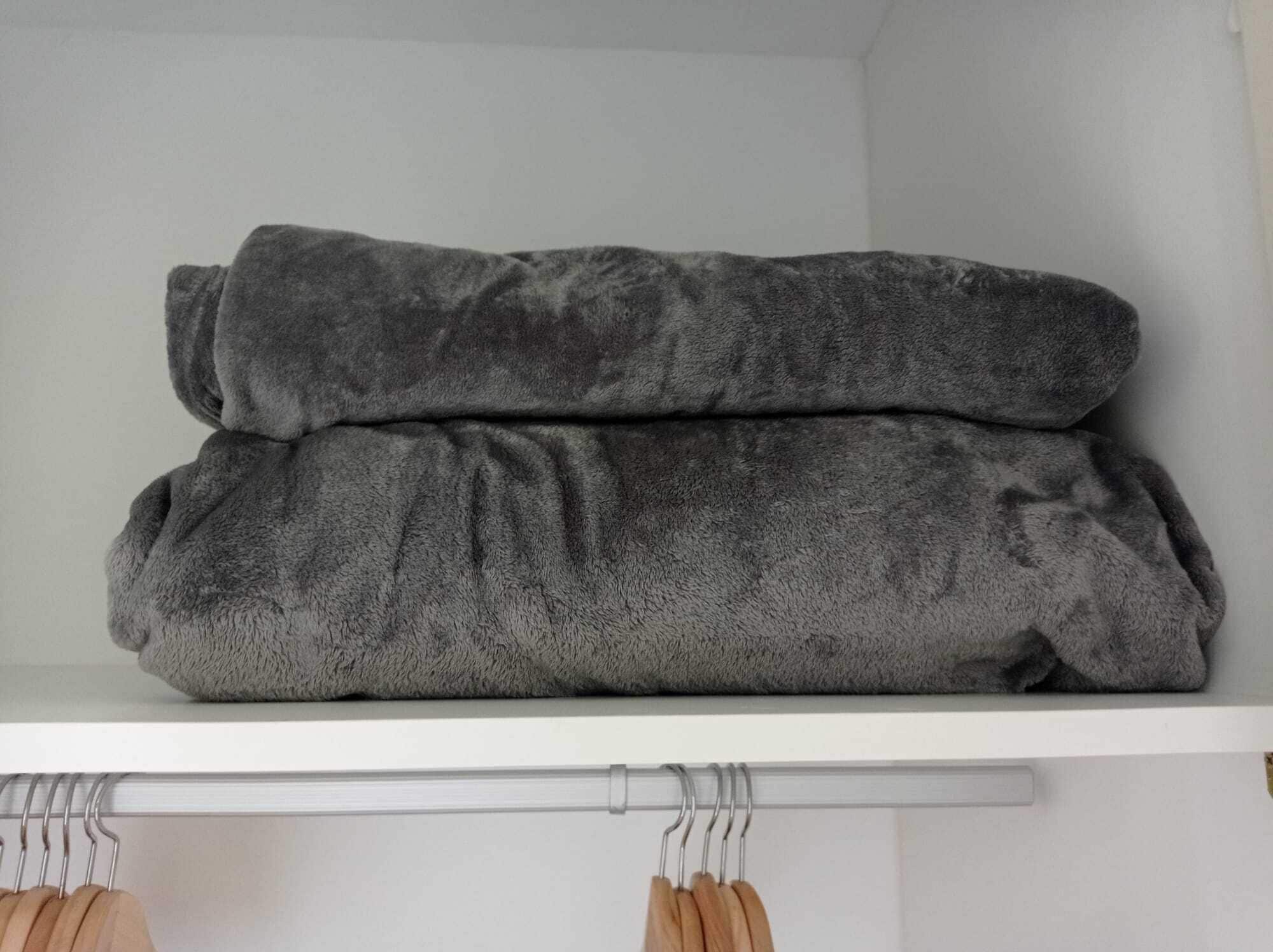 A shelf with two folded blankets.