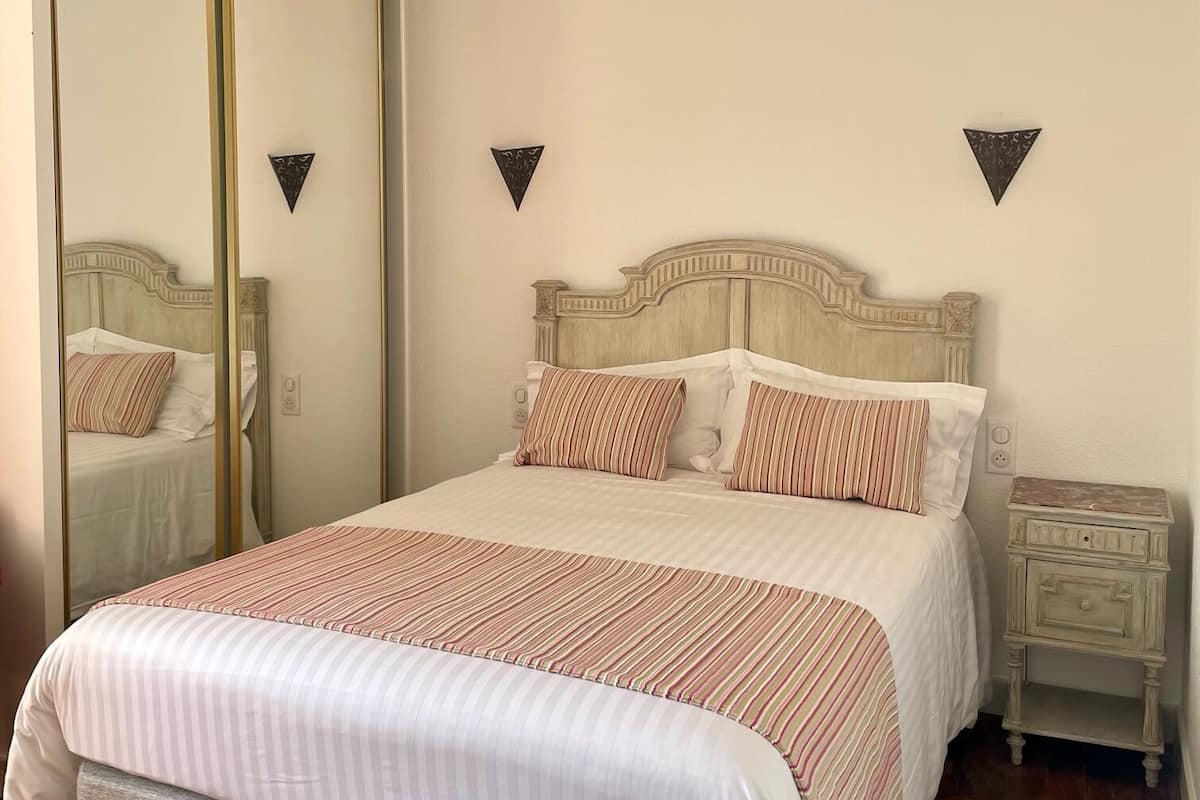 Une chambre à coucher avec un lit, une table de chevet, un miroir et une armoire.