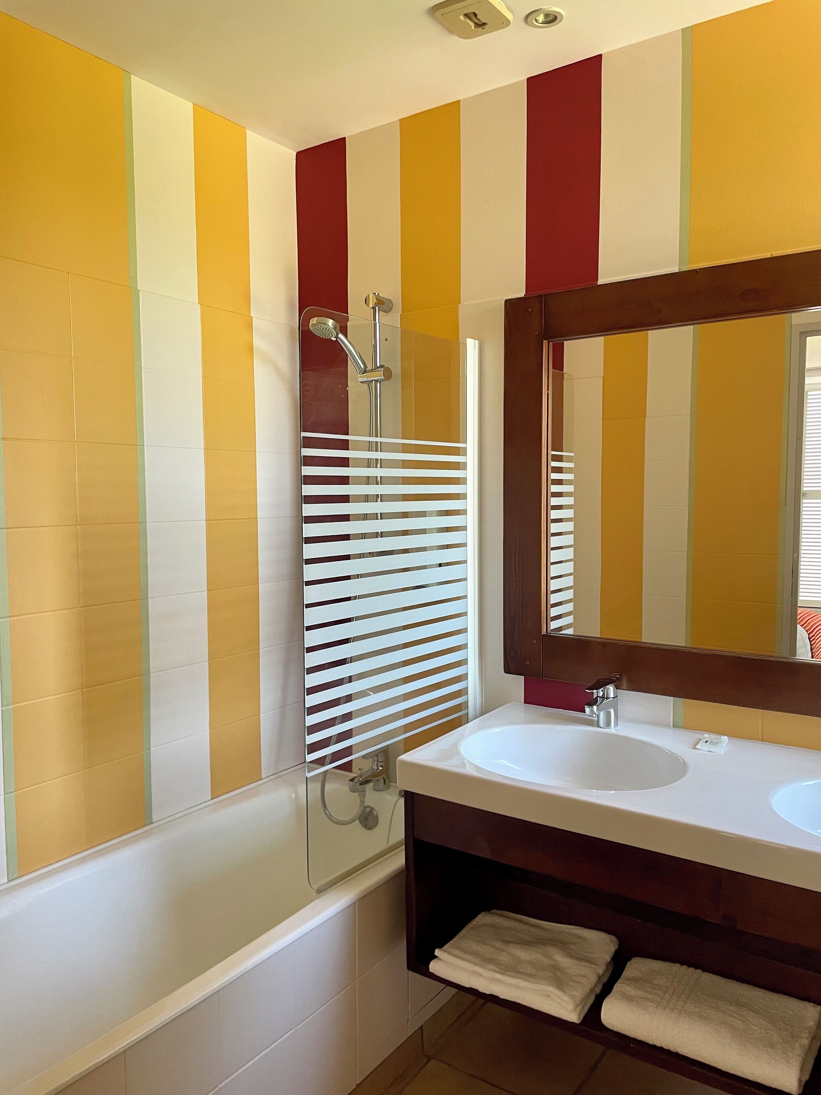 A bathroom with a white bathtub, a white sink, and a mirror above the sink.