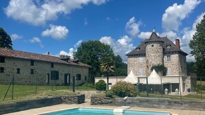 Ein Schwimmbecken mit einem Steinhaus im Hintergrund.