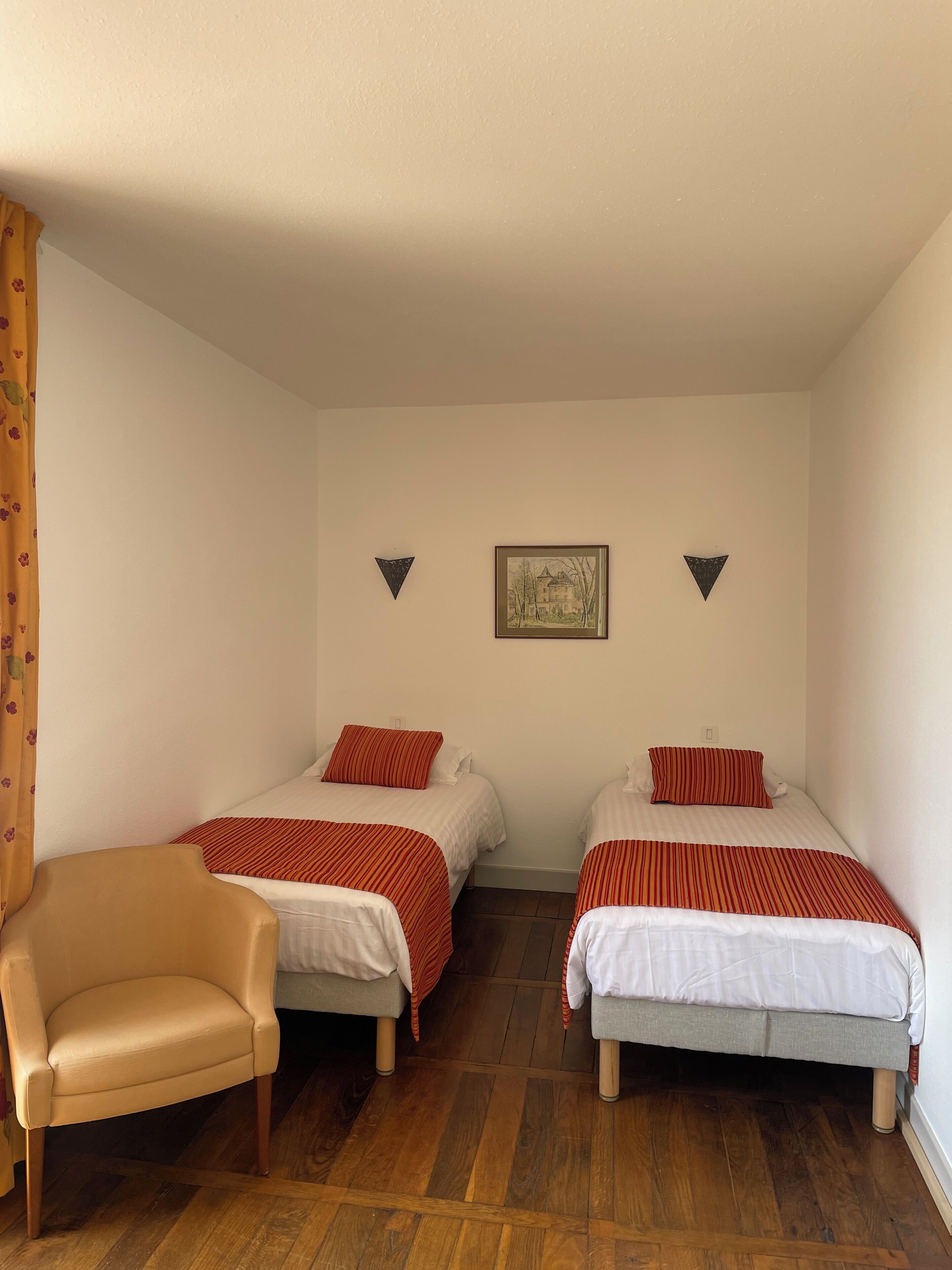 Une chambre avec deux lits simples, une chaise et un tableau encadré au mur.