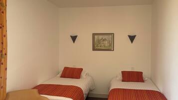 Une chambre avec deux lits simples, une chaise et un tableau encadré au mur.