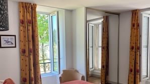 Ein Hotelzimmer mit einem Bett, einem Sessel und einem Fenster mit Vorhängen.
