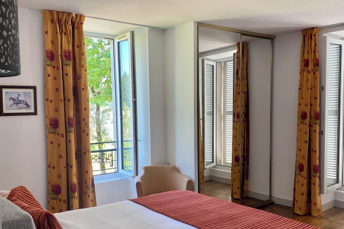 Une chambre d’hôtel avec un lit, une chaise et une fenêtre avec des rideaux.