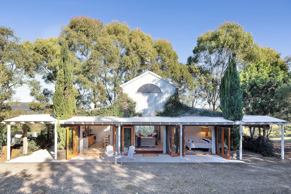 A modern house with a covered patio, a dining area, and a bedroom with a large window.