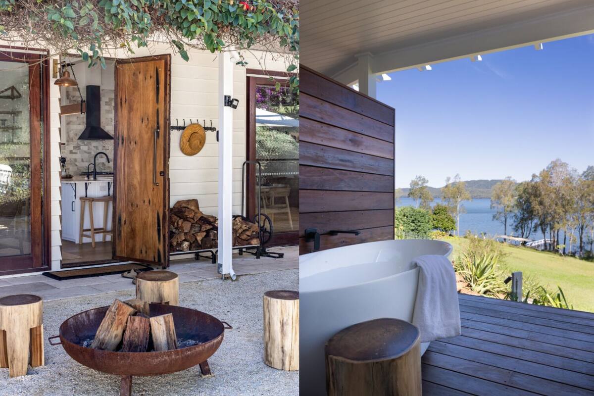 A rustic outdoor area with a fire pit, wooden stools, and a view of a lake.
