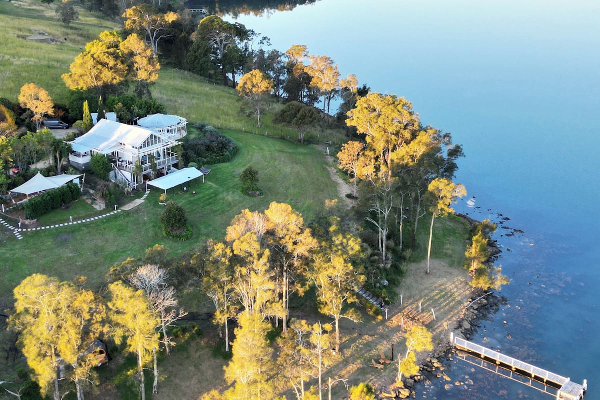 An aerial view of a lakeside property with a large house, a dock, and a boat.