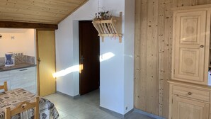 Une pièce chaleureuse avec un plafond en bois, une table à manger avec des chaises, un coin cuisine équipé d’une machine à café et un buffet en bois.
