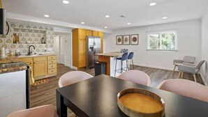 Une cuisine moderne avec des meubles en bois, un réfrigérateur en acier inoxydable et un coin repas comprenant une table et des chaises.