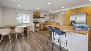 Une cuisine moderne avec des meubles en bois, un réfrigérateur en acier inoxydable et un coin bar avec des tabourets.