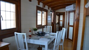 A dining area with a white table, white chairs, and a black pan on the table. - Roulottes a la Ferme sur le Plateau du Vercors (Autrans-Méaudre en Vercors)