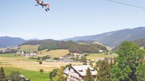 A person bungee jumping with a scenic landscape in the background. - Roulottes a la Ferme sur le Plateau du Vercors (Autrans-Méaudre en Vercors)