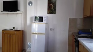 A compact kitchen with a white refrigerator, a microwave, and a sink. - Apartment for 4 persons (Bar)