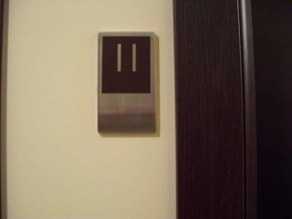 A door with a metallic handle and a wall-mounted control panel with two buttons.
