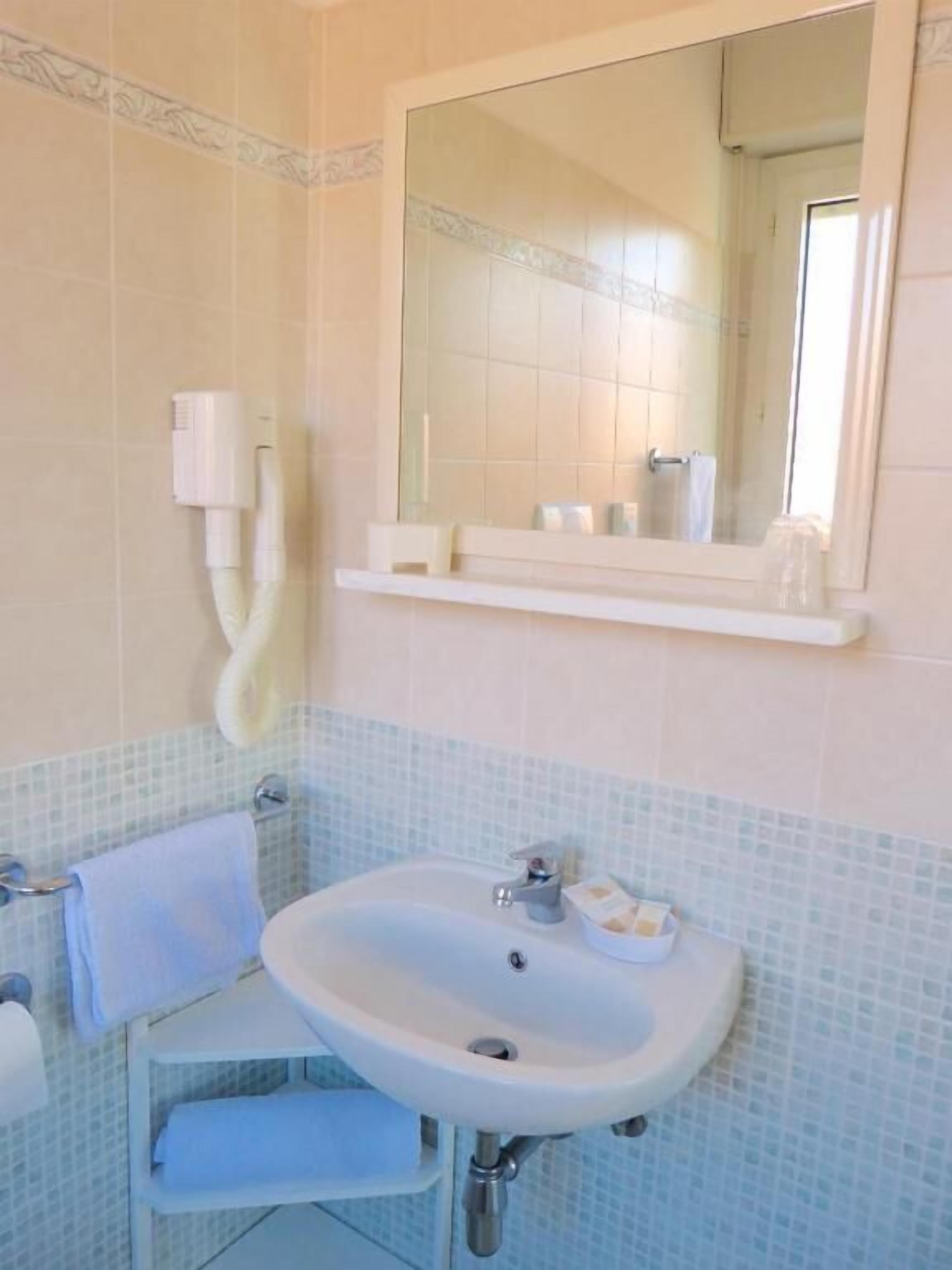Une salle de bain avec un lavabo, un miroir et un porte-serviettes.