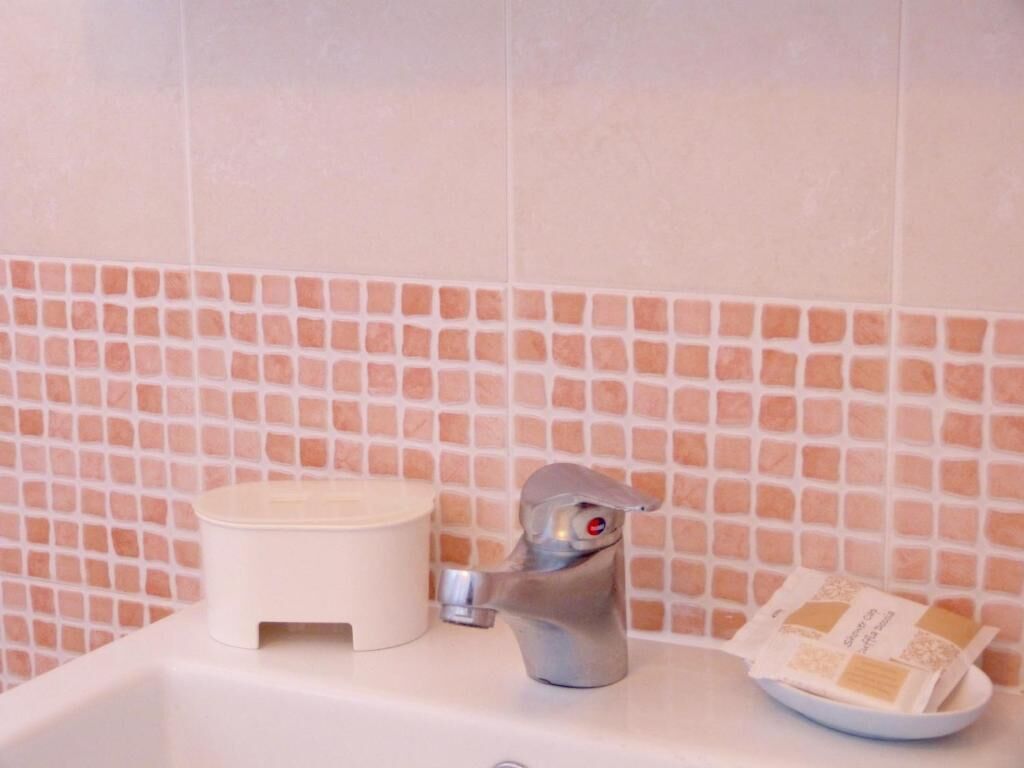 A bathroom with a sink, a faucet, a soap dish, and a soap dispenser.
