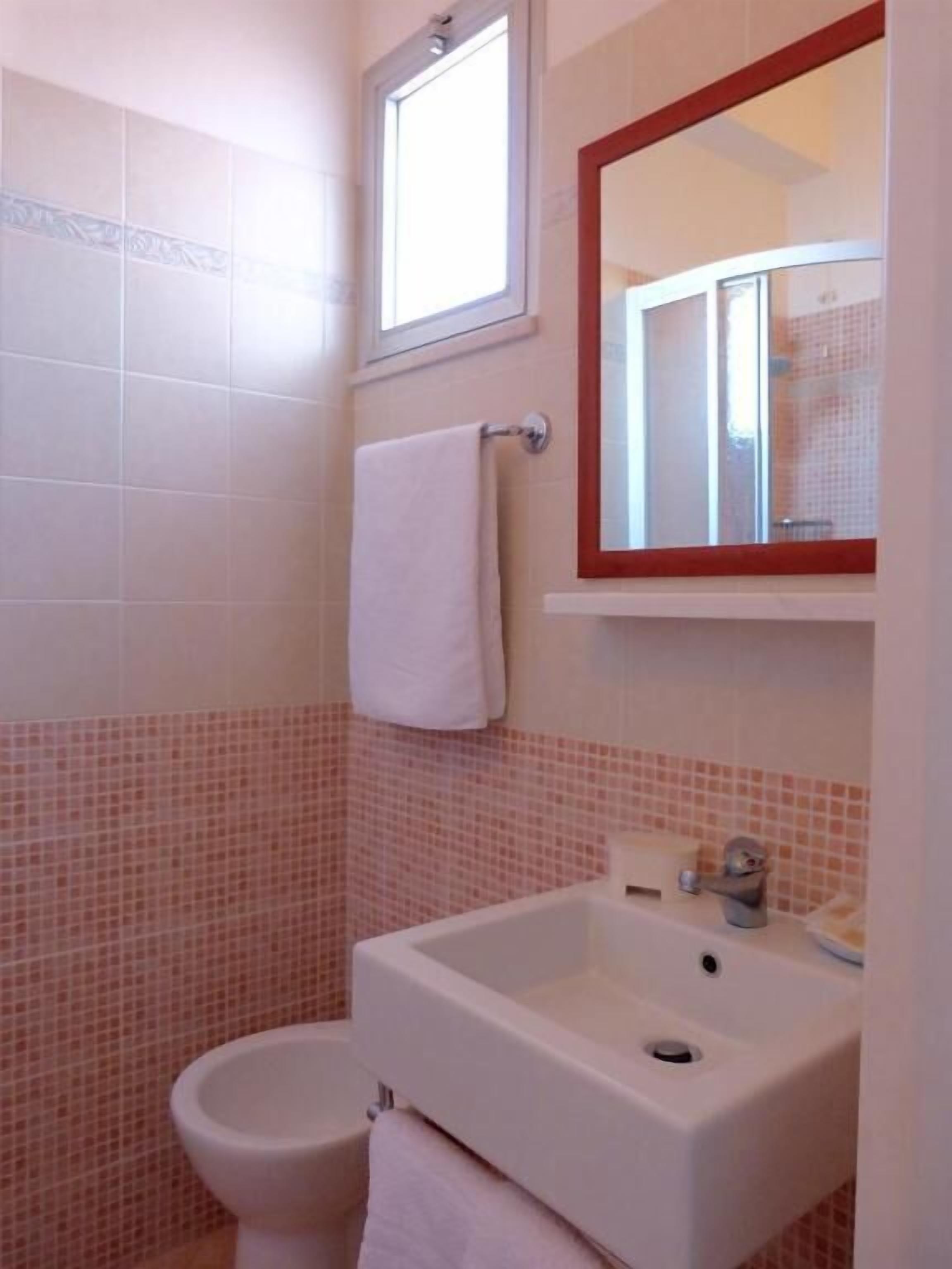 Un bagno con un lavandino bianco, un water e uno specchio con cornice rossa.