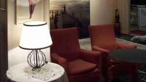 A hotel lobby with a round table, two red armchairs, and a wall-mounted lamp. - Hotel D'annunzio (Cattolica)