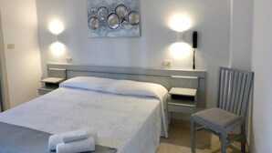 A hotel room with a bed, bedside tables, a chair, and wall-mounted lights. - Hotel D'annunzio (Cattolica)