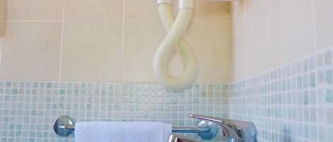 Un baño con lavamanos blanco, toallero y ducha.