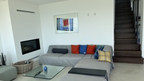 A modern living room with a sofa, a glass coffee table, a flat-screen TV, and a staircase. - Country house on Monte Maderno with 260* lake view on 15000 square meters of parkland (Toscolano Maderno)
