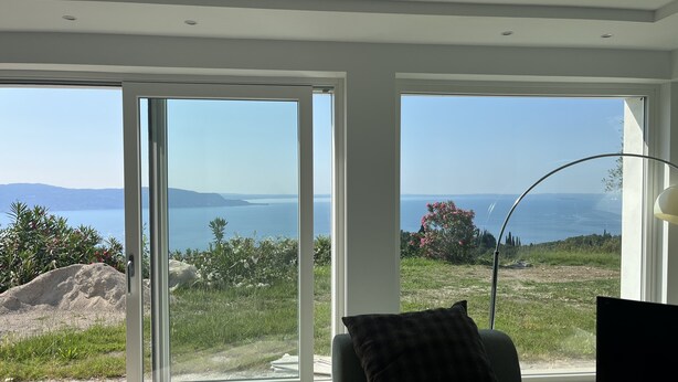 A modern living room with large sliding glass doors leading to a scenic view of the sea and hills. - Country house on Monte Maderno with 260* lake view on 15000 square meters of parkland (Toscolano Maderno)