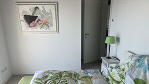 A bedroom with a bed, a bedside table with a lamp, a door, and a framed abstract artwork on the wall. - Country house on Monte Maderno with 260* lake view on 15000 square meters of parkland (Toscolano Maderno)