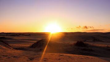 A desert landscape with dunes and a sunset.