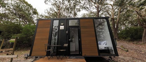 A small cabin with a wooden deck, a door, and a window.