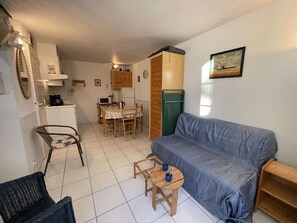 A compact living space with a kitchenette, a dining area, a sofa, and a small table with a chair. - Cozy 3-Room House with Access to Pools and Close to Beach, Sleeps 4 (Saint-Jean-de-Monts)