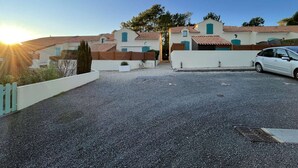 A residential area with houses, a gravel driveway, and a parked car.