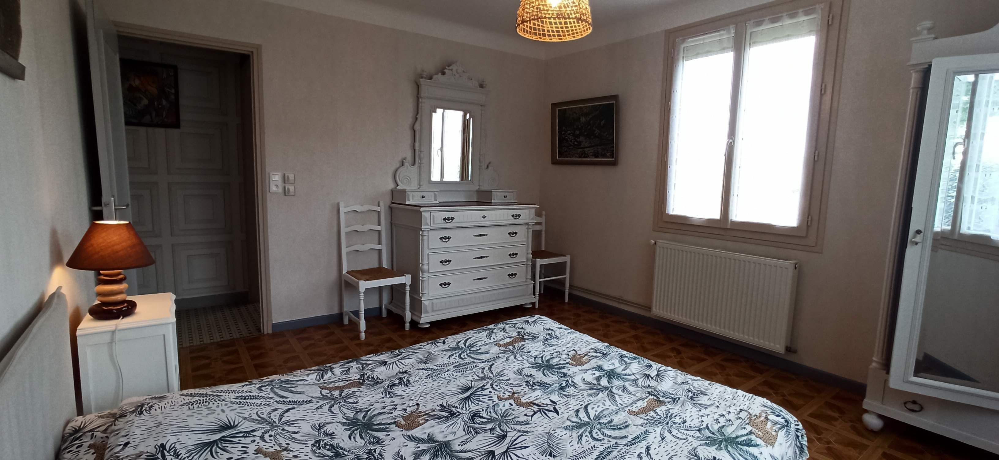 Une chambre à coucher avec un lit, une commode, une chaise et une fenêtre.