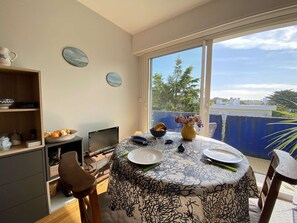 Enjoy meals in this cozy dining area with a round table for four, a bookshelf, and a TV.